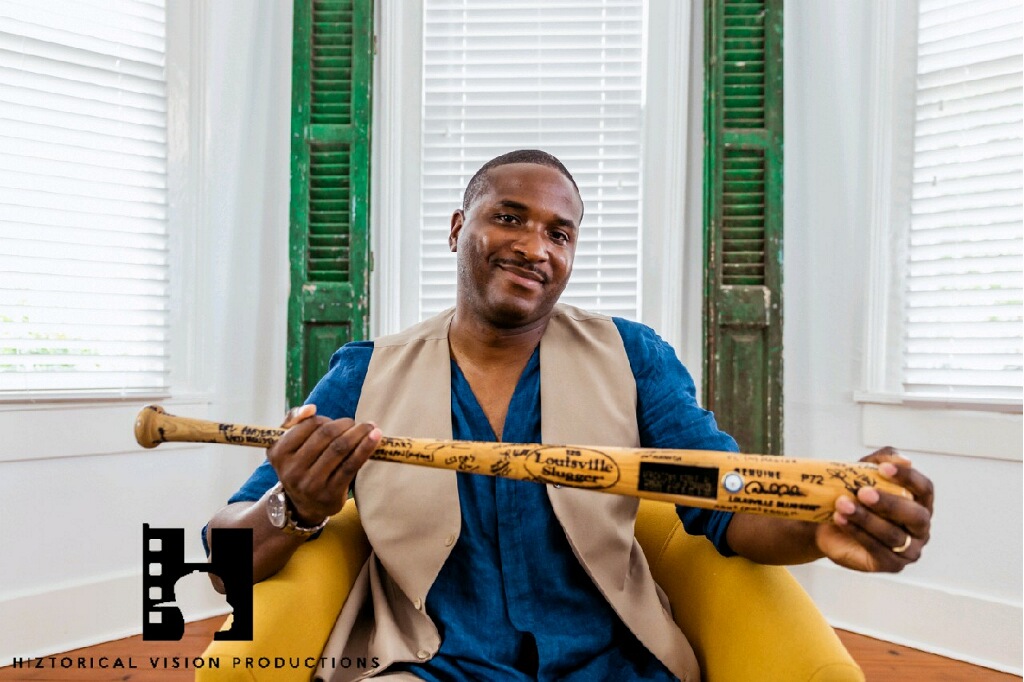 Chief Lewis holding a signed commemorative Louisville Slugger bat during a documentary interview