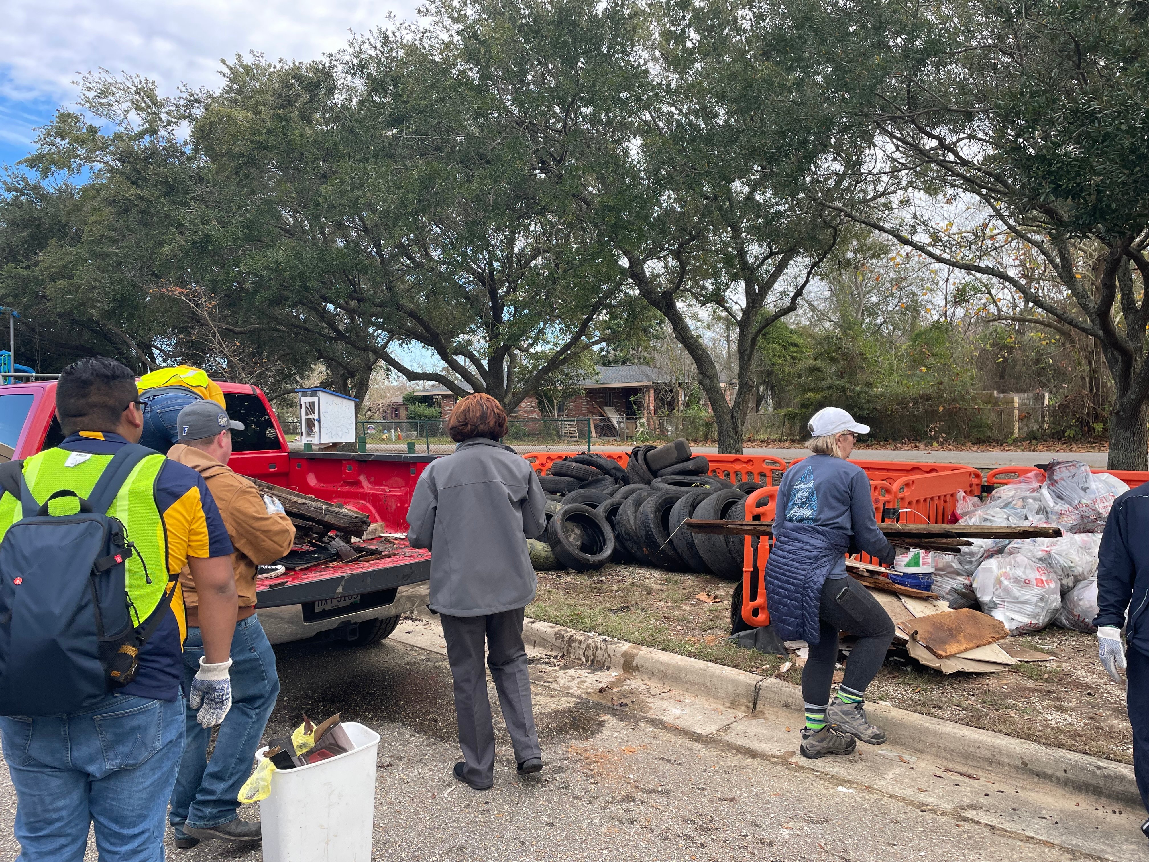 Volunteers loading debris and tires into a truck during a neighborhood cleanup